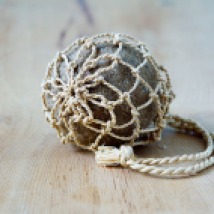 Bourse, filet noué au «nœud des lacustres», en feuilles de palmier-raphia, contenant une boule naturelle de feutre de feuilles de posidonie de Méditerranée.